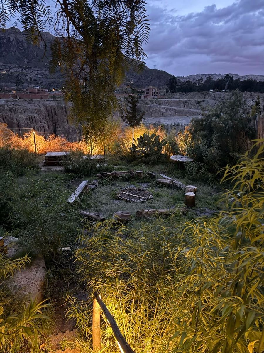 La zona baja del Barranco al anochecer, con el círculo de la fogata y luces cálidas.